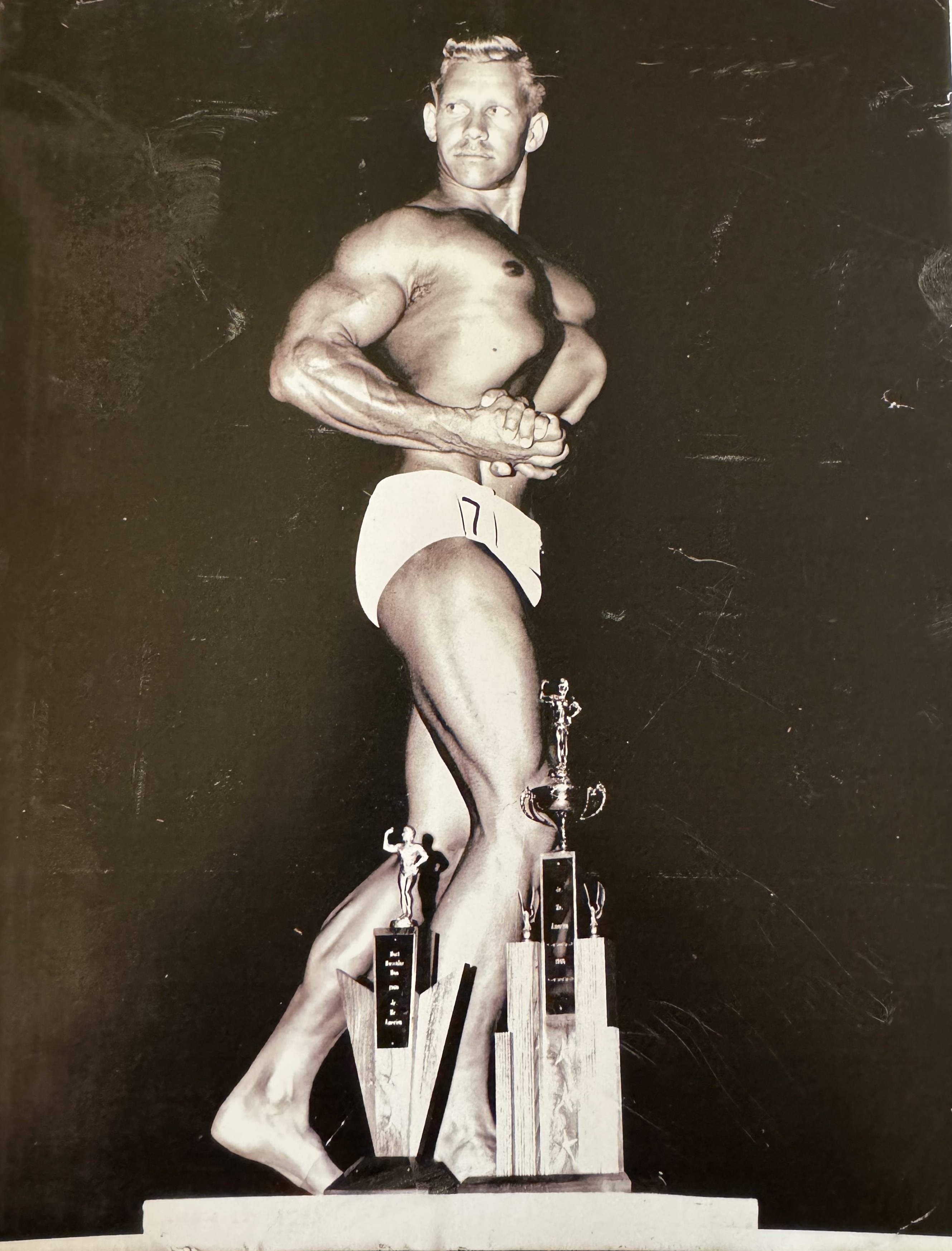Gail Crick on podium with competition trophies