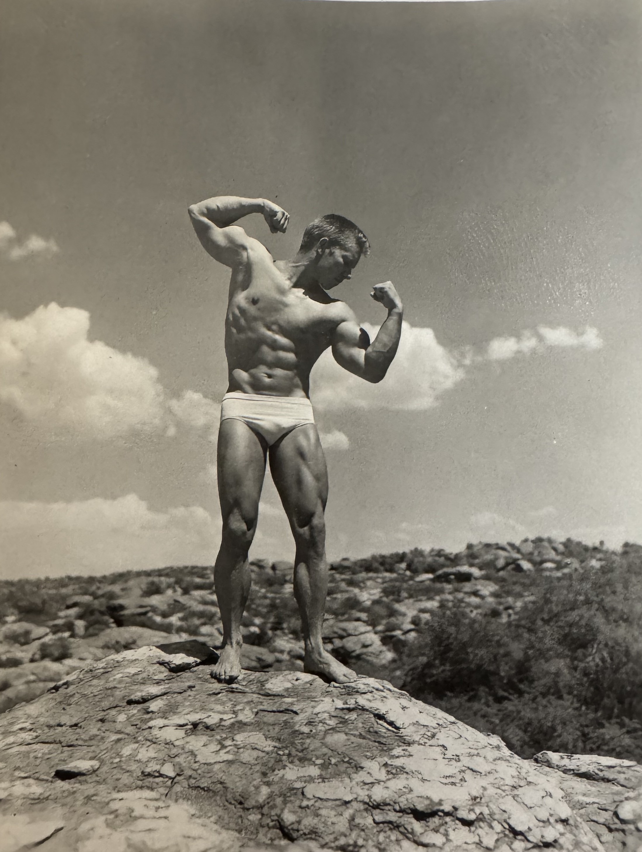 Gail Crick - double bicep pose on a rocky hilltop against Arizona sky